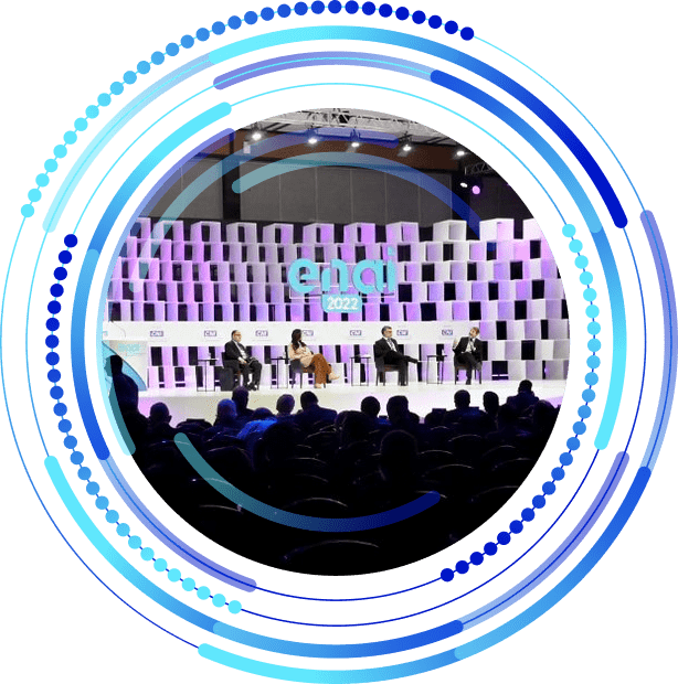 Grafismo do ENAI com uma imagem de apresentadores em um palco na edição 2022 do ENAI