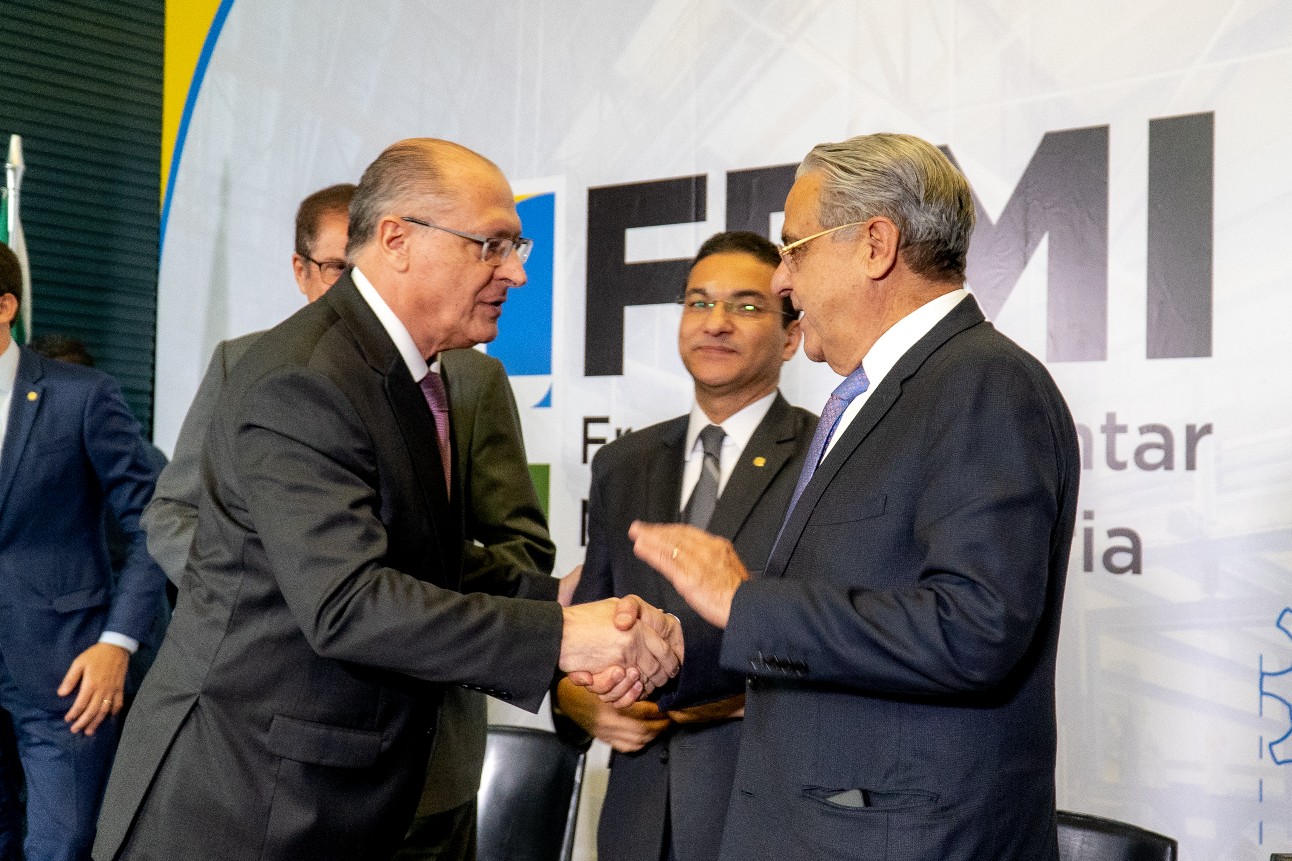 Foto colorida traz vice-presidente da República, Geraldo Alckmin, e presidente da CNI, Robson Andrade, trocando aperto de mãos. Ambos são homens brancos, vestem terno e usam óculos.