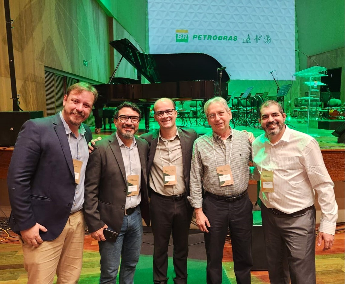 grupo de homens posam sorrindo em frente a um piano