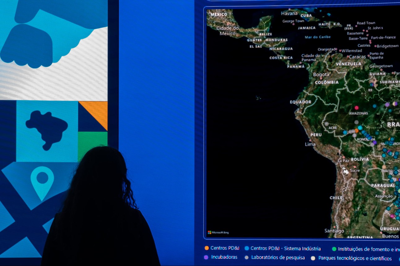 mulher observa de costas um painel com o mapa do Brasil
