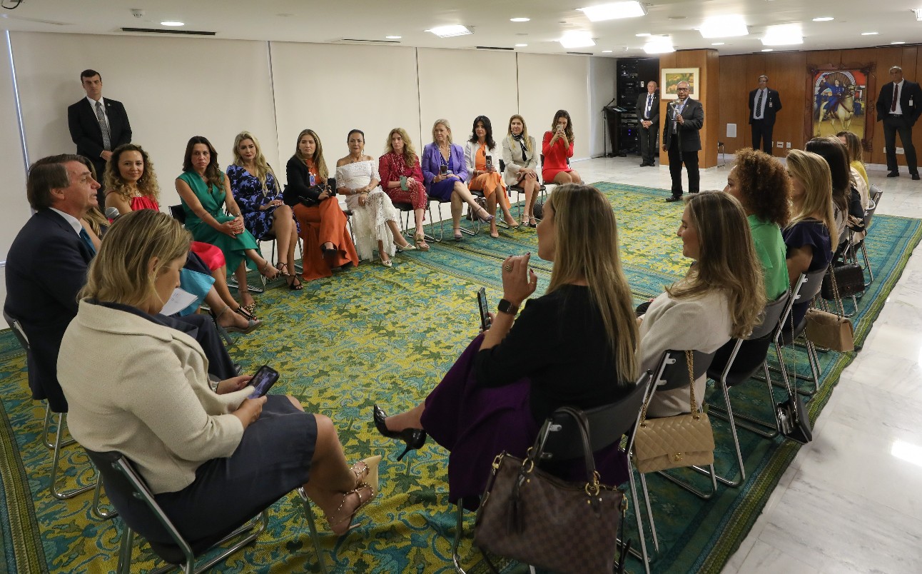 Grupo de mulheres debatendo, sentadas em cadeiras formando semicírculo, com presidente Jair Bolsonaro em um dos lugares