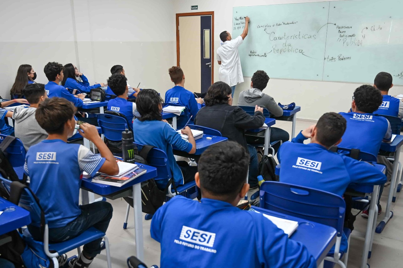 foto colorida de alunos do SESI estudando em sala de aula, todos vestem uniforme azul