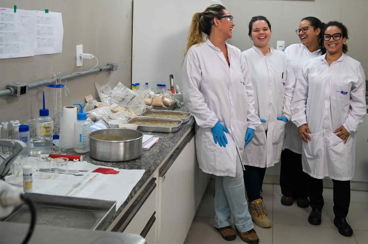 Quatro mulheres com equipamento de segurança sorrindo em laboratório