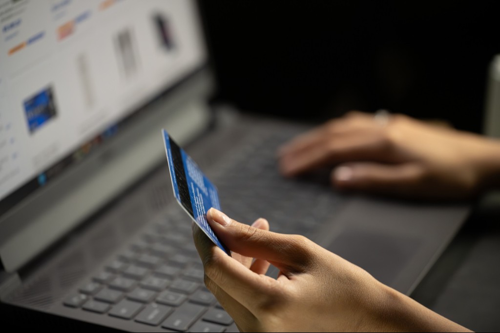 pessoa segurando cartão de crédito, fazendo compras online