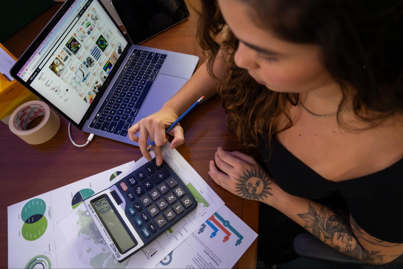 jovem trabalha com auxilio de calculadora e computador