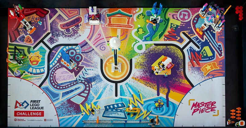 tapete de competição de robótica multicolorido, com algumas peças de lego, visto de cima