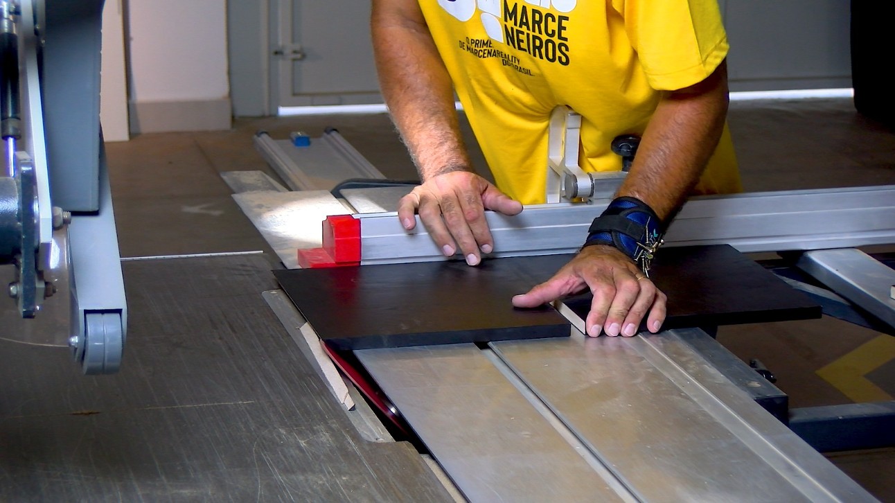 foto: homem de blusa amarela mexe em máquina de corte