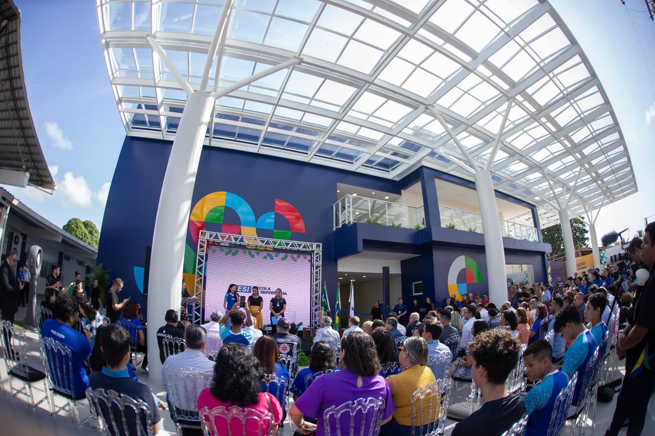 foto de pessoas assistindo a abertura da escola sesi de referência, as pessoas estão sentadas em cadeiras e tem um palco a frente