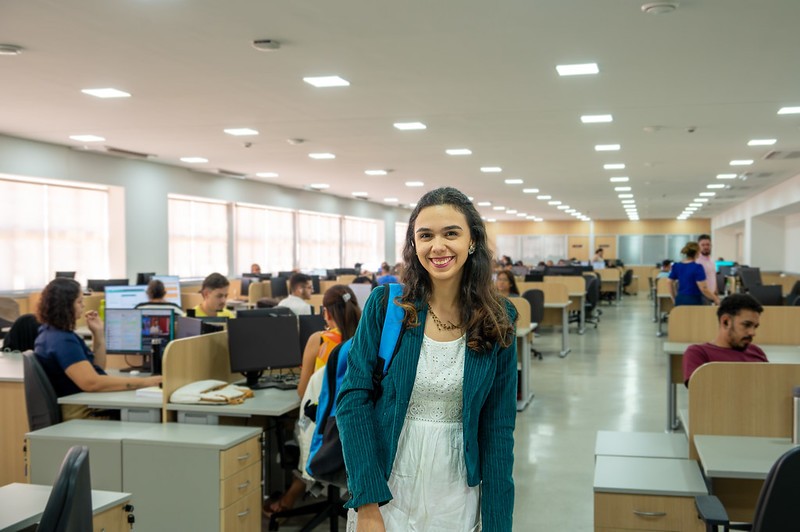 mulher, jovem, de mochila, em frente à cenário de escritório