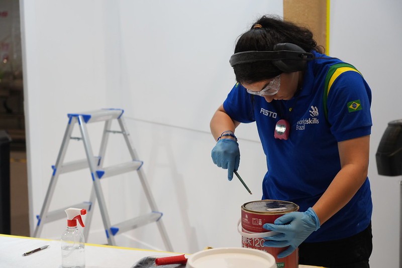 Competidora brasileira manuseia produtos químicos utilizados nas provas da WorldSkills. Devido às restrições de transporte internacional, alguns desses insumos precisaram ser adquiridos na China