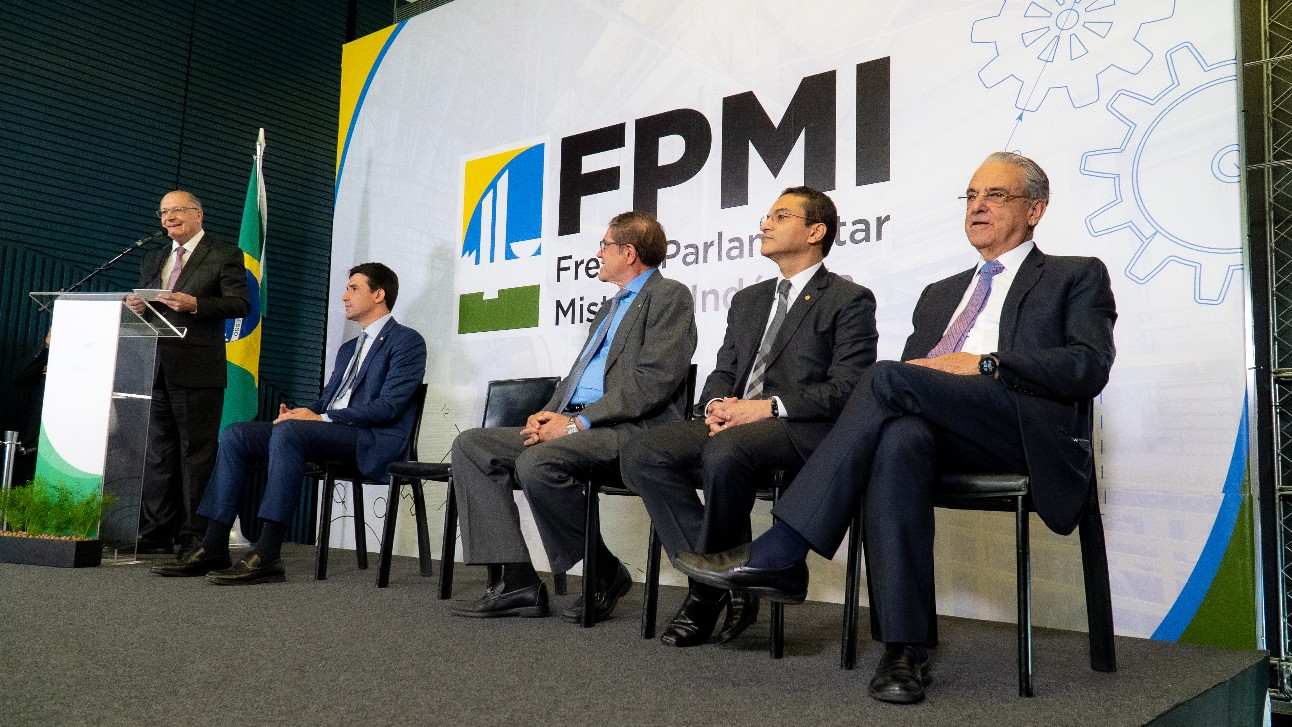 Vice-presidente da República, Geraldo Alckmin, fala de pé em palco onde outros quatro homens, todos brancos e vestindo ternos escuros, estão sentados