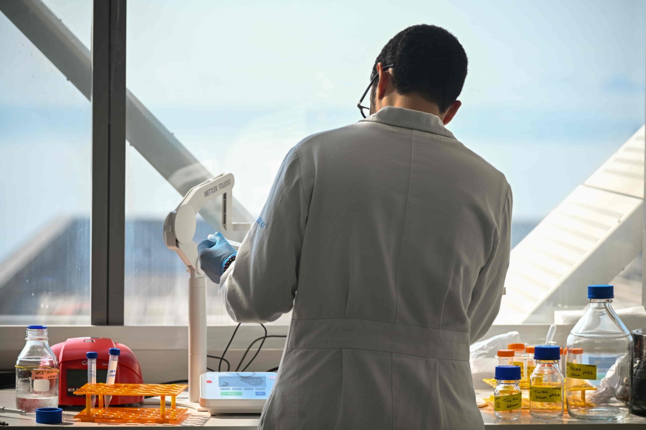 Cientista de costas com frascos ao lado