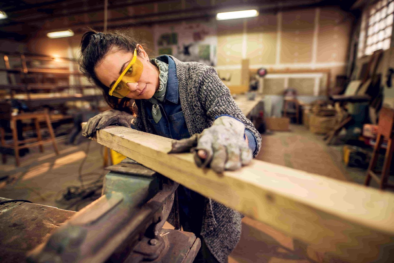 Vista retrato da trabalhadora profissional trabalhadora de meia idade trabalhadora de carpinteiro profissional que procura e escolhe madeira na oficina ou garagem.