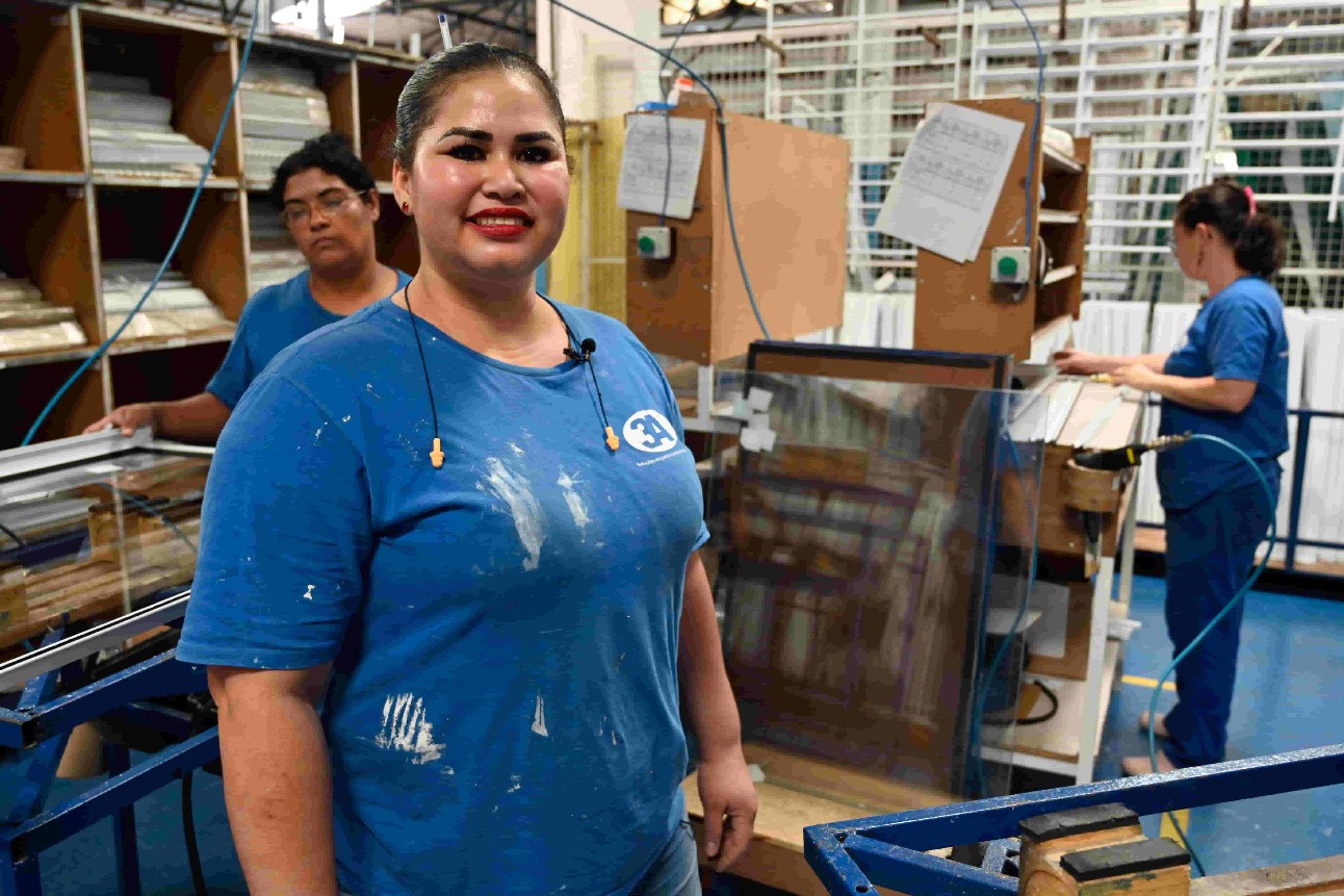mulher da indústria, usa uniforme azul que está sujo de tinta