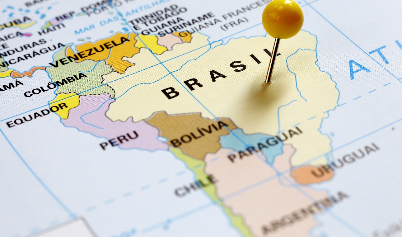 imagem colorida traz mapa da América do Sul com alfinete de cabeça amarela fixado no Brasil