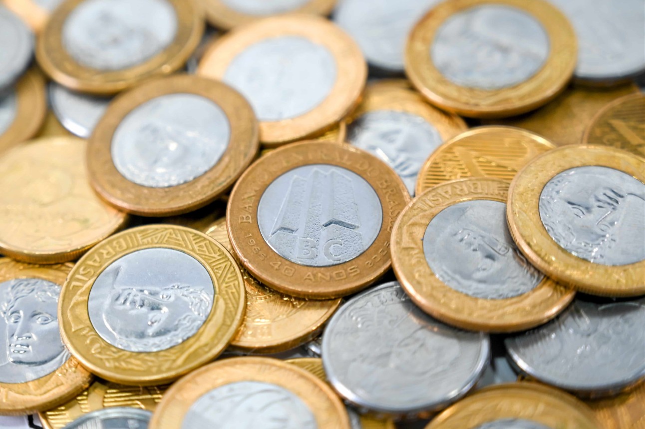 foto colorida de moedas de um real - que são prateadas no centro e com as bordas douradas