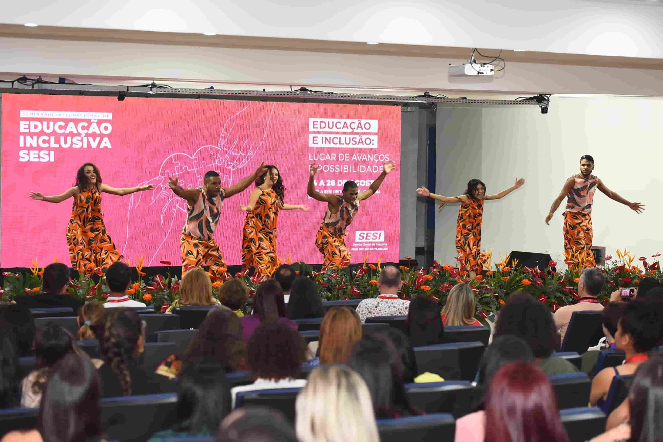 grupo de pessoas se apresentam em palco dançando