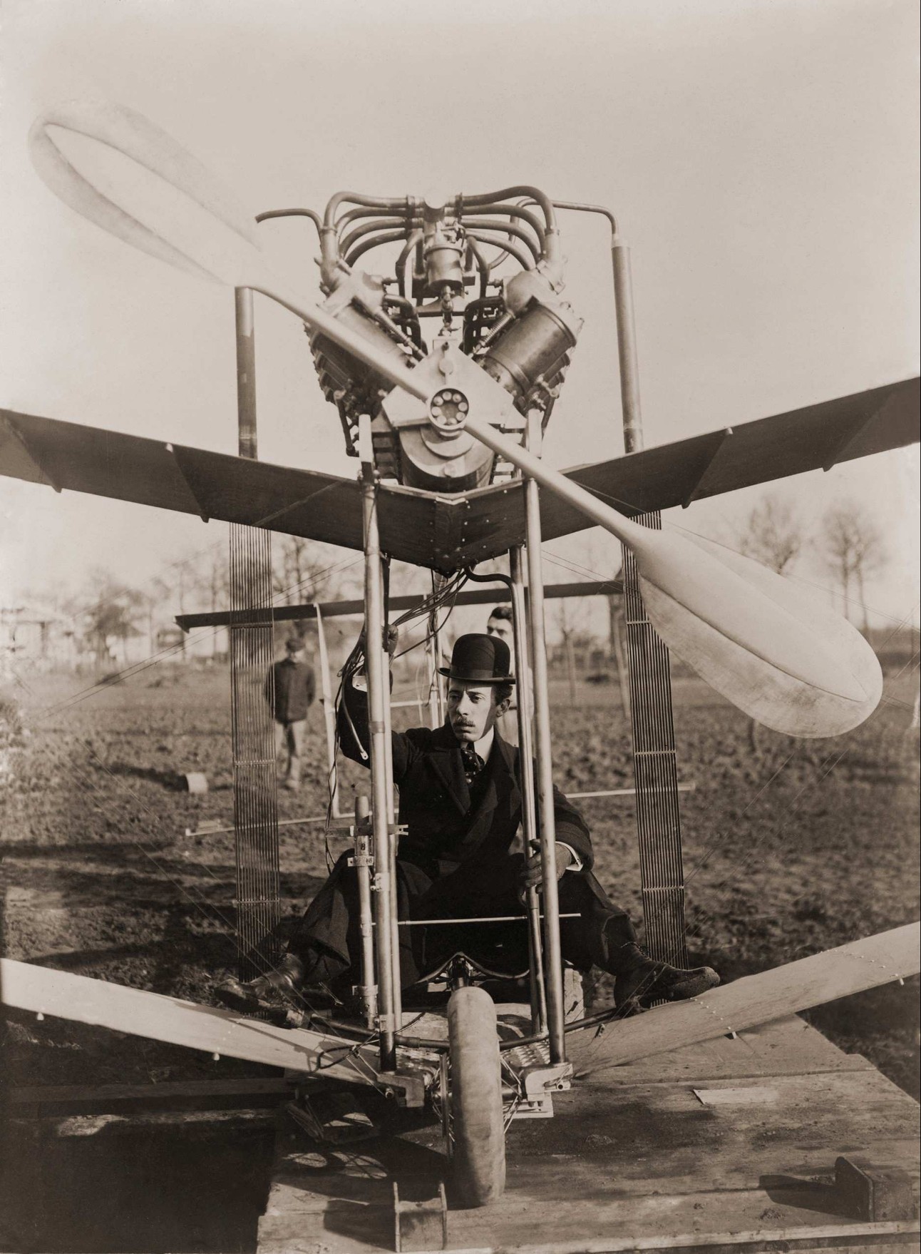 Imagem em preto e branco do inventor Alberto Santos Dumont com o avião 14-Bis
