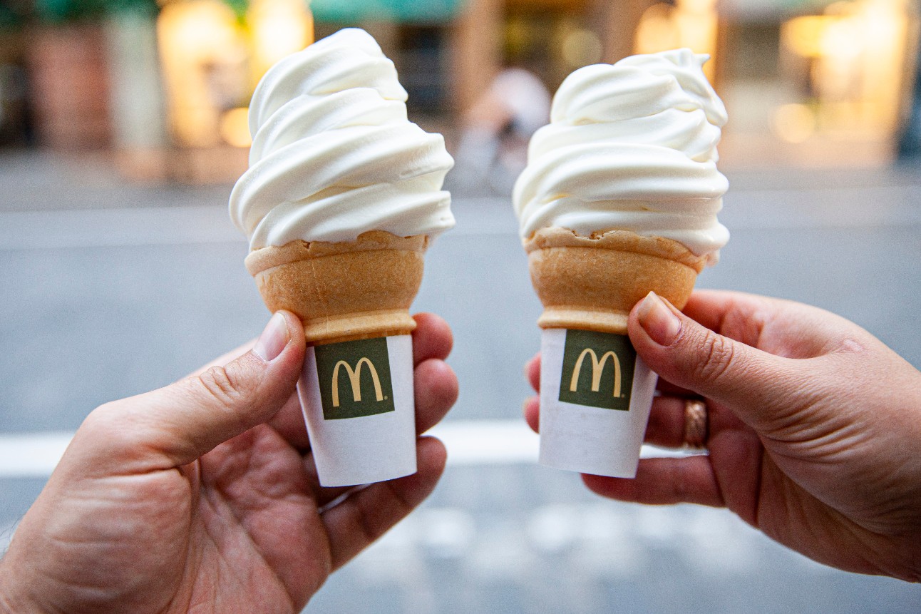 duas mãos de pessoas brancas seguram sorvetes do McDonalds