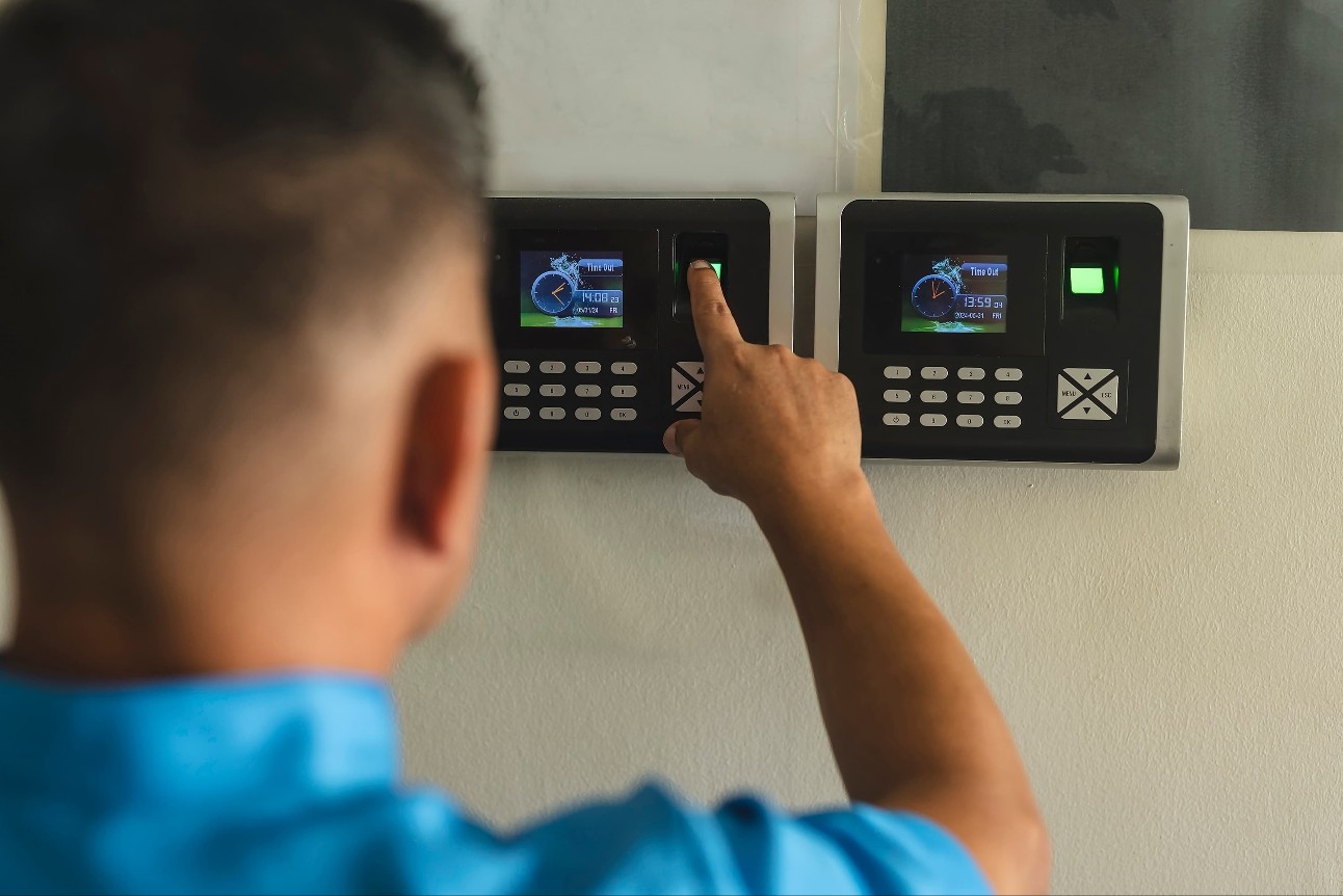 Um zelador ou funcionário marcando o ponto em um scanner biométrico de impressão digital. Registrando os horários de comparecimento dos funcionários que se apresentam para o trabalho.