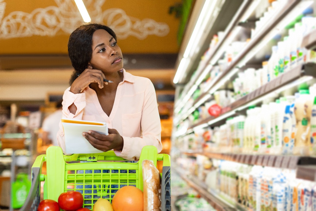 mulher negra em supermercado olhando preços de mercadorias