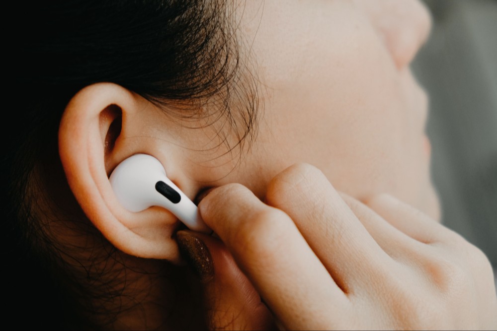 Close-up em uma pessoa utilizando um AirPods, fone de ouvido sem fio da Apple.