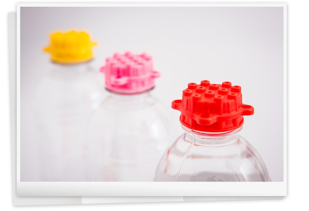 Imagem de garrafas plásticas transparentes com tampinhas coloridas que se encaixam entre si e também se encaixam em legos