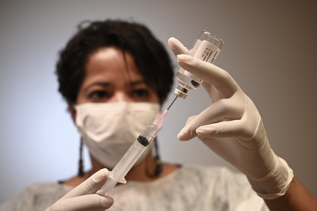 Mulher manipulando seringa e vacina contra a Covid-19
