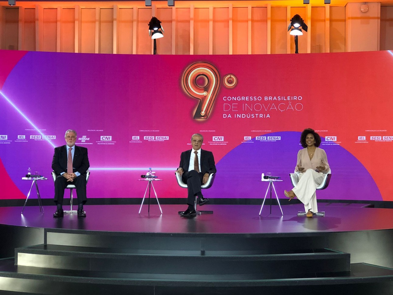 foto colorida, com presidentes do Sebrae e da CNI e apresentadora no palco do lançamento do congresso de inovação
