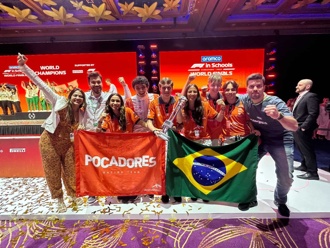 estudantes vestidos de laranja seguram bandeiras do Brasil e com o nome da equipe, Pocadores